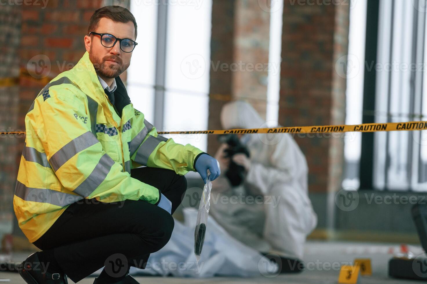 Weapon is in the package. Detectives are collecting evidence in a crime scene near dead body photo