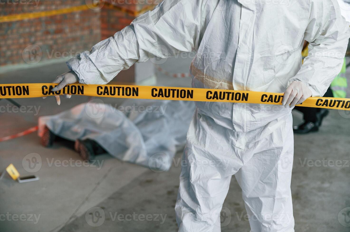 Holding caution police tape. Detectives are collecting evidence in a crime scene near dead body photo