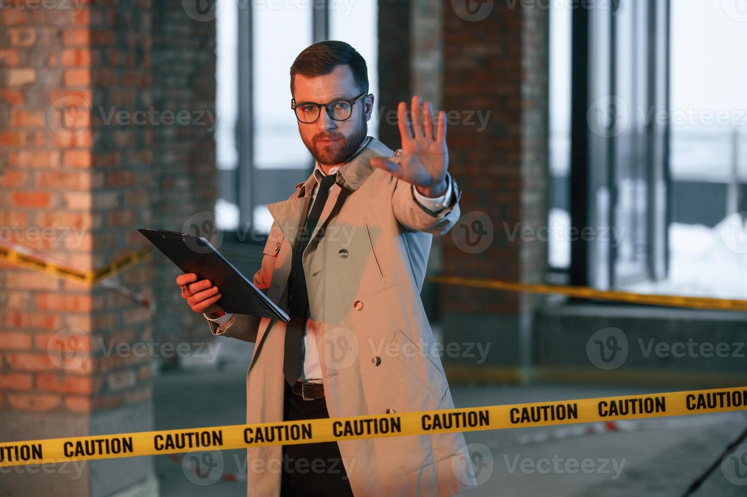 Stop gesture.. No trespassing. Male detective in coat is collecting evidence in a crime scene on the construction site photo