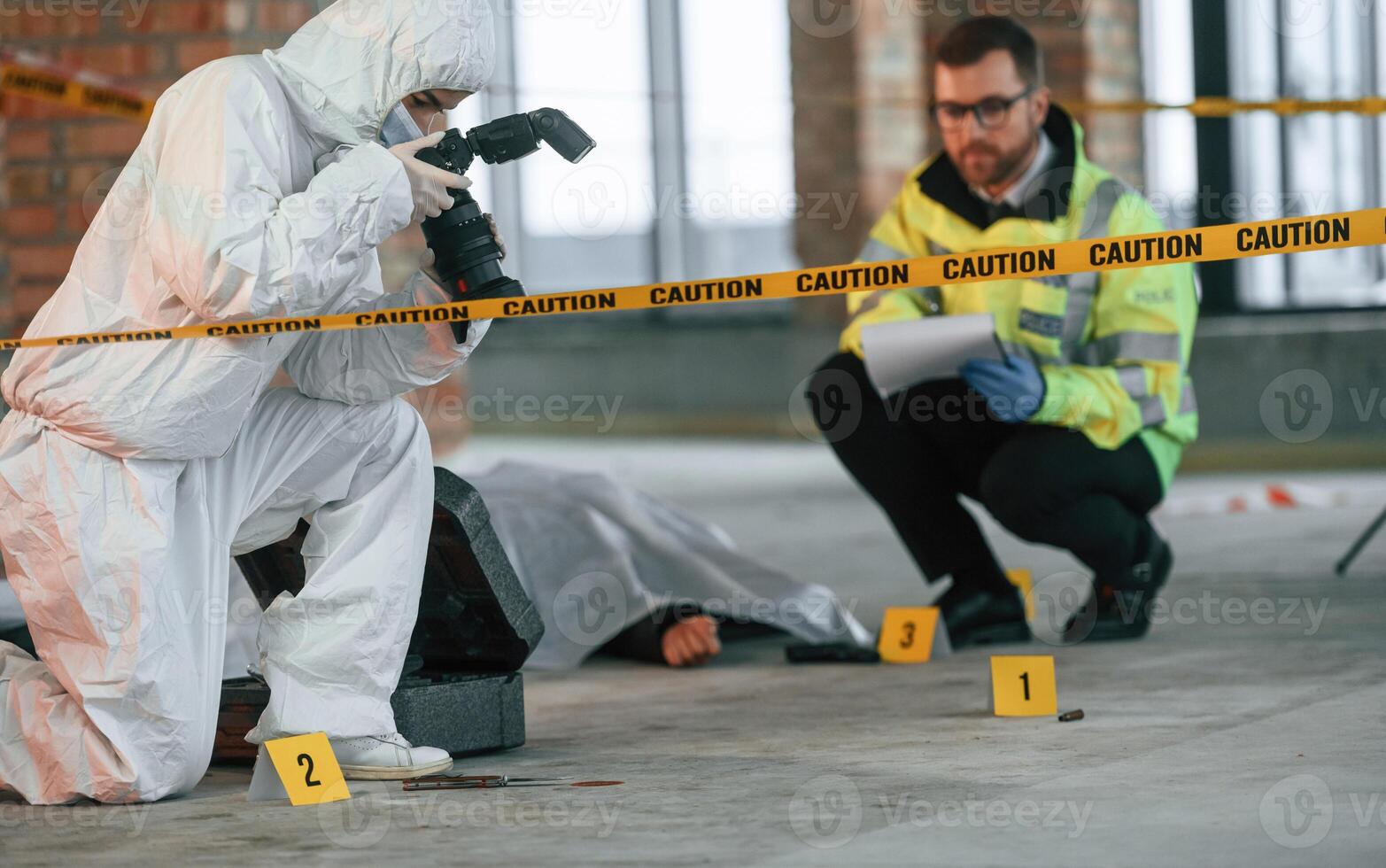Woman is making photos ,by camera. Detectives are collecting evidence in a crime scene near dead body