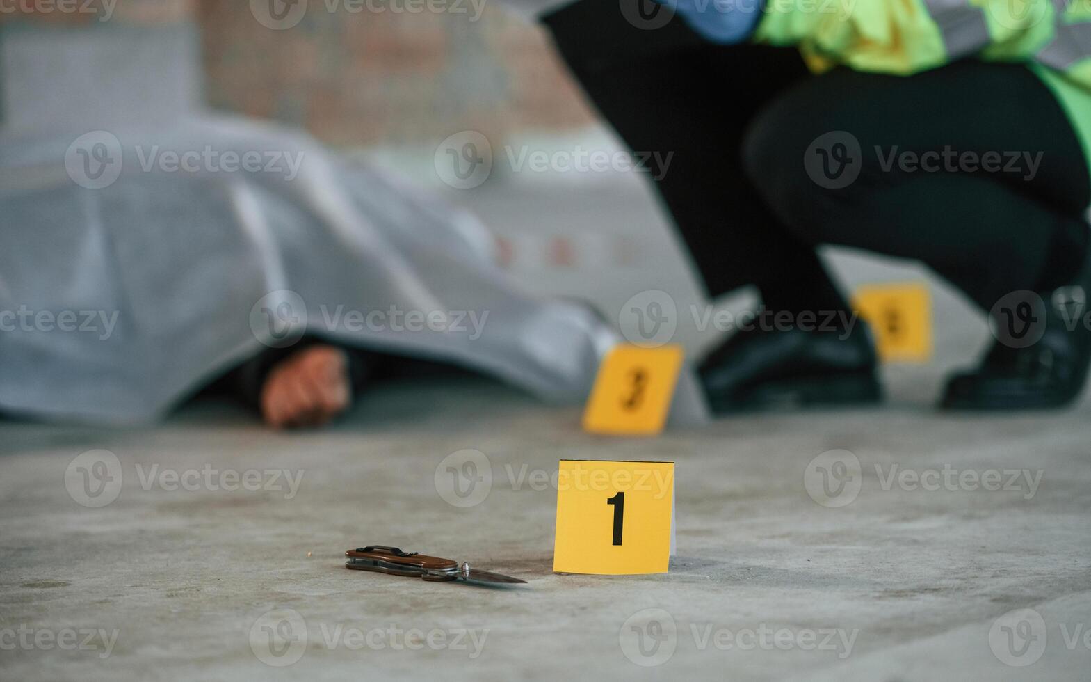 Male detective is, collecting ,evidence in a crime scene near dead body on the construction site photo