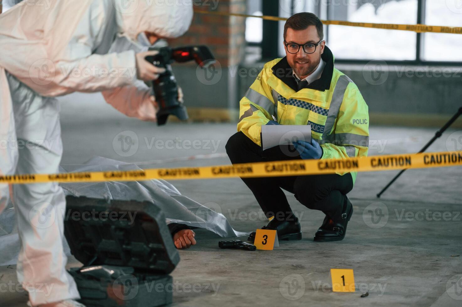 Woman is, making photos by camera. Detectives are collecting evidence in a crime scene near dead body