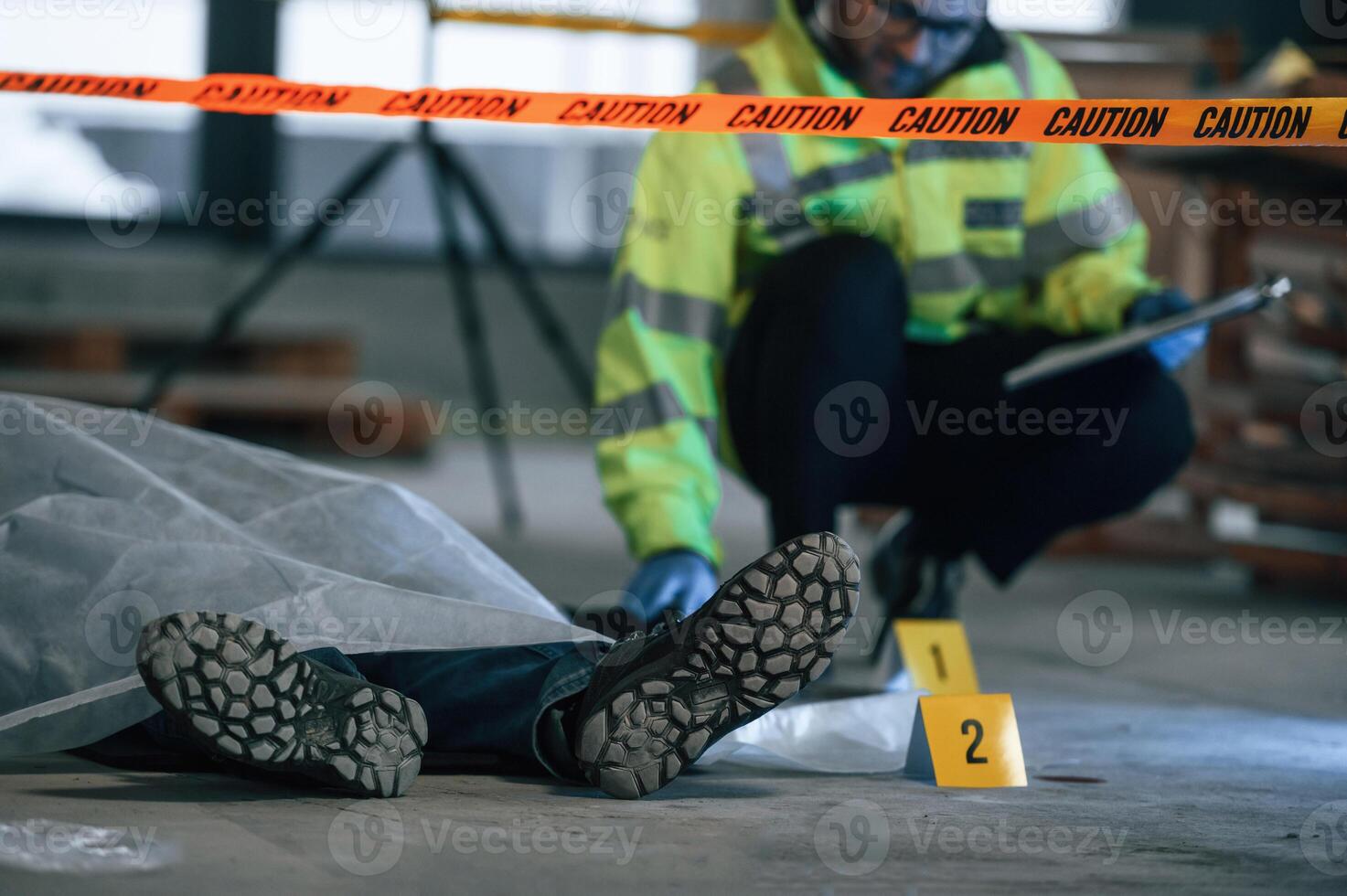 Male detective is collecting evidence in a crime scene near dead body on the construction site photo
