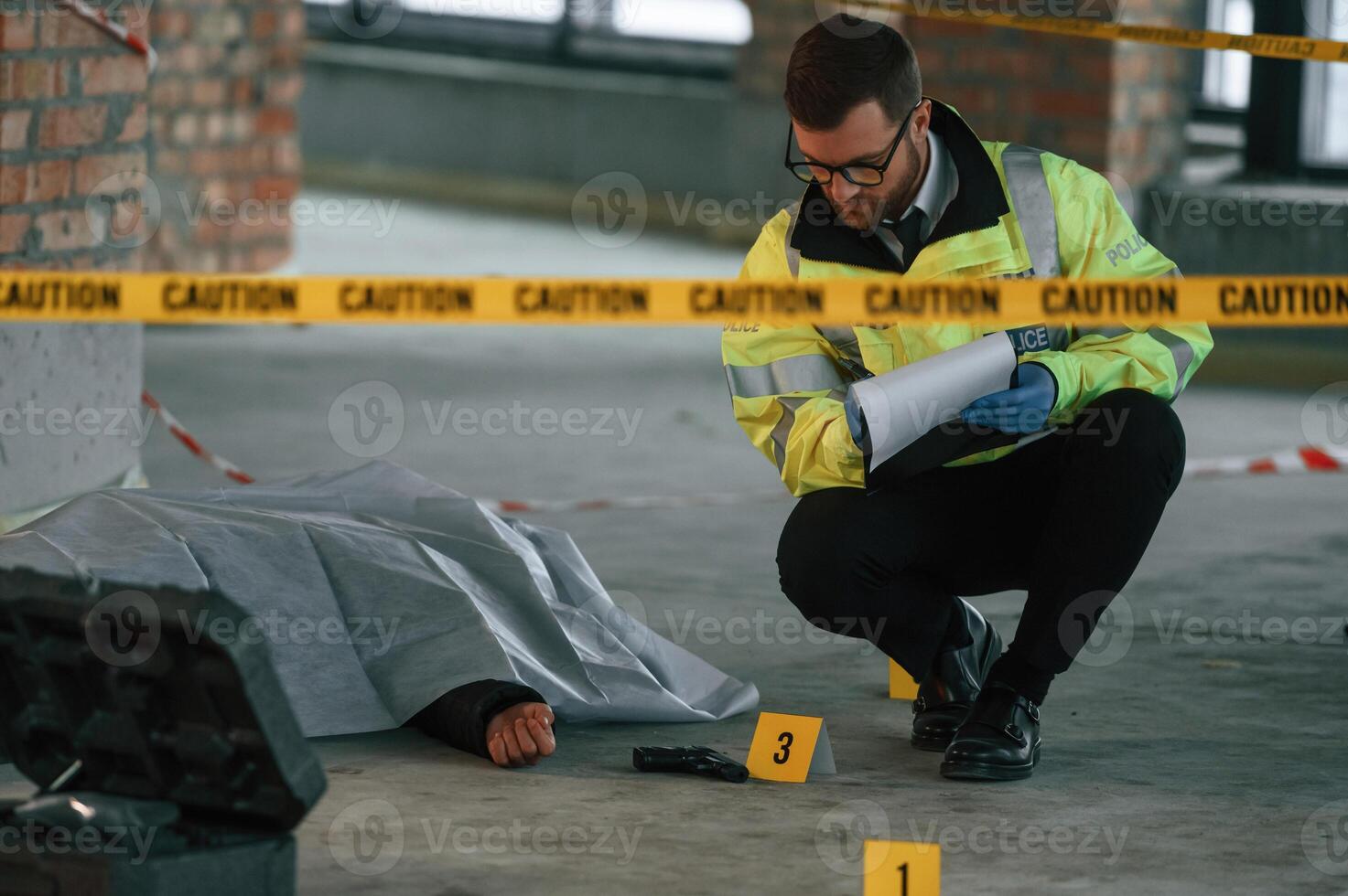 Notepad with information. Male detective is collecting evidence in a crime scene near dead body on the construction site photo