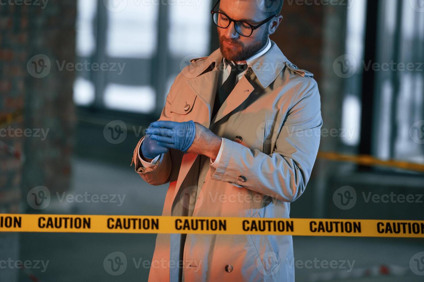 Taking ,off the gloves. Male detective in coat is collecting evidence in a crime scene on the construction site photo