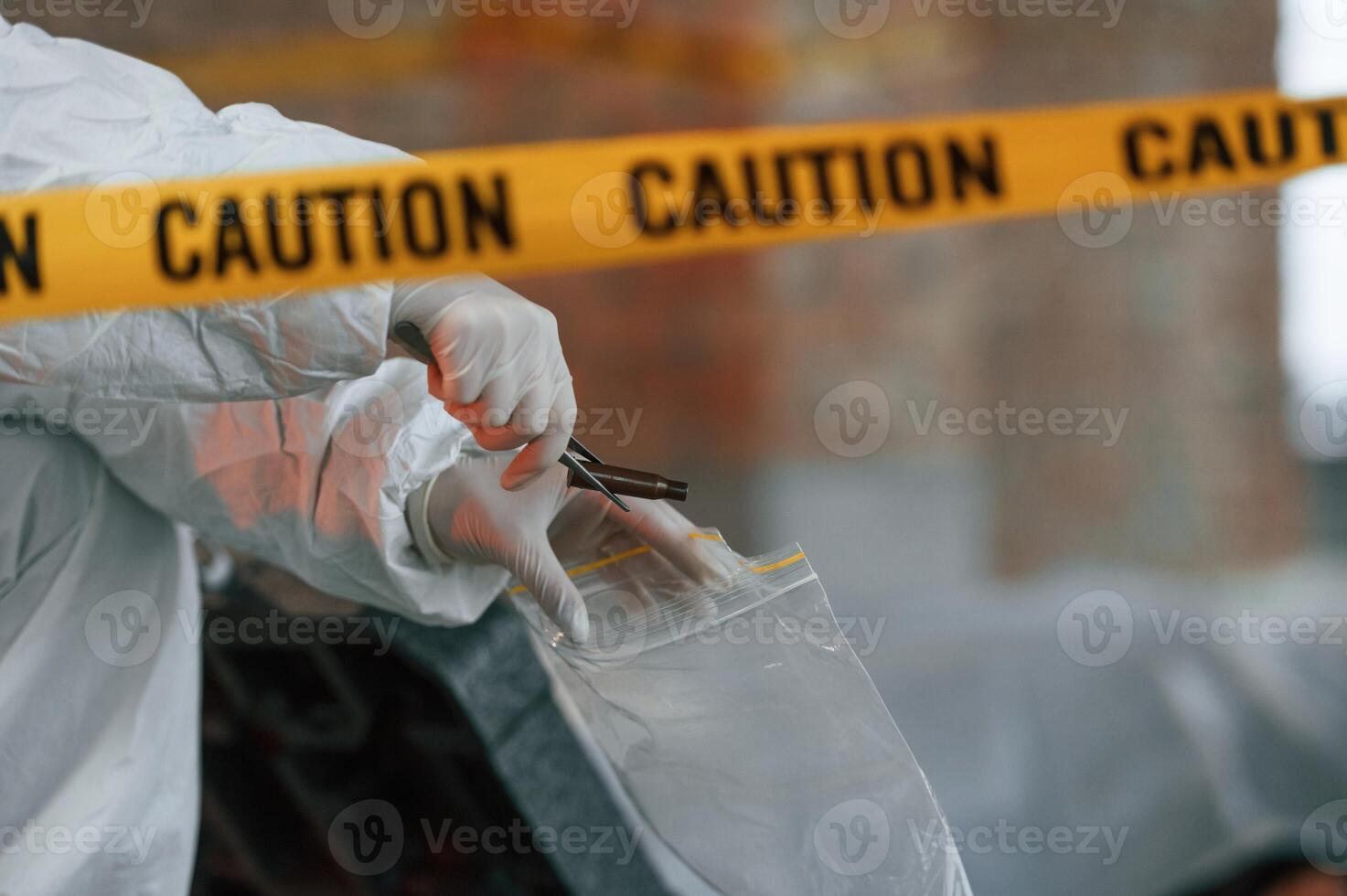 Bullet sleeve in hand. Detective are collecting evidence in a crime scene photo
