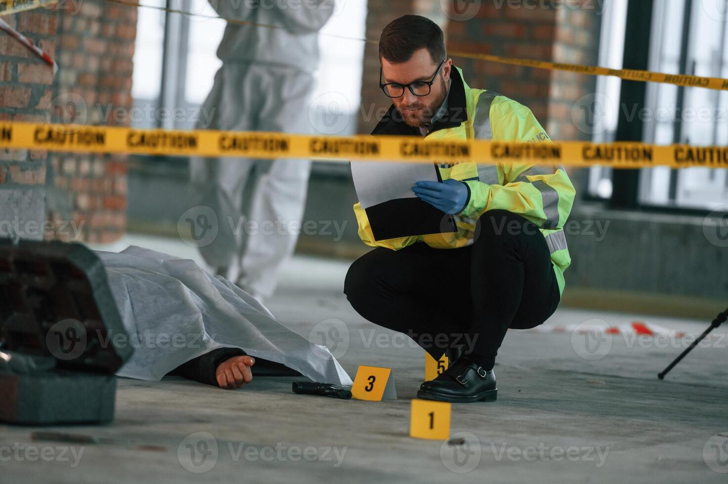 Dead, body, is on the ground. Detectives are collecting evidence in a crime scene photo