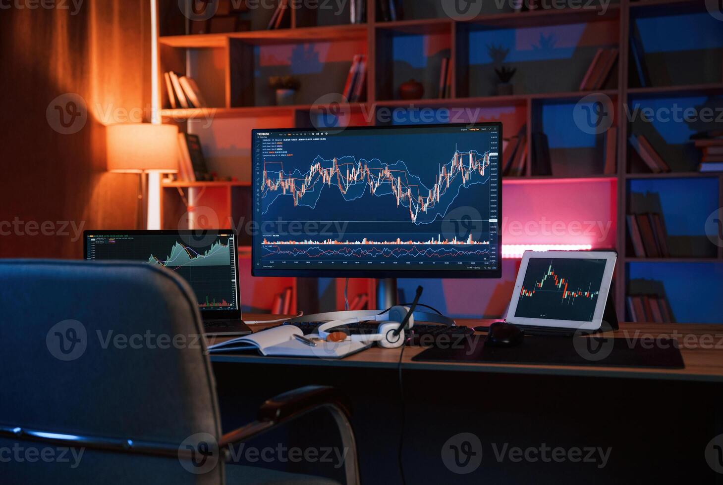 Computer with, stock exchange graph on display is in the dark room with neon lighting photo