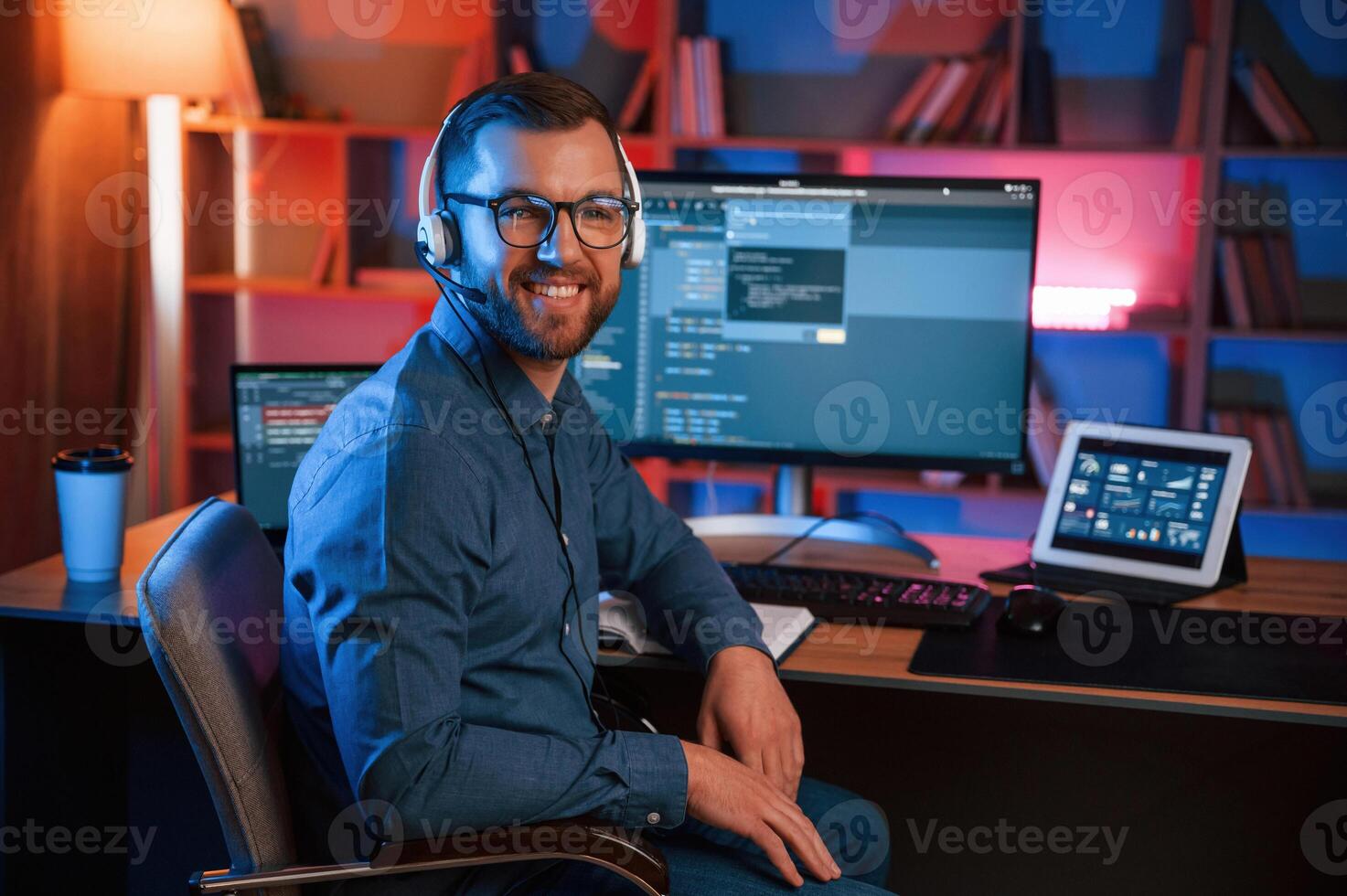 Positive, professional ,programmer is working indoors and smiling. Neon lighting photo