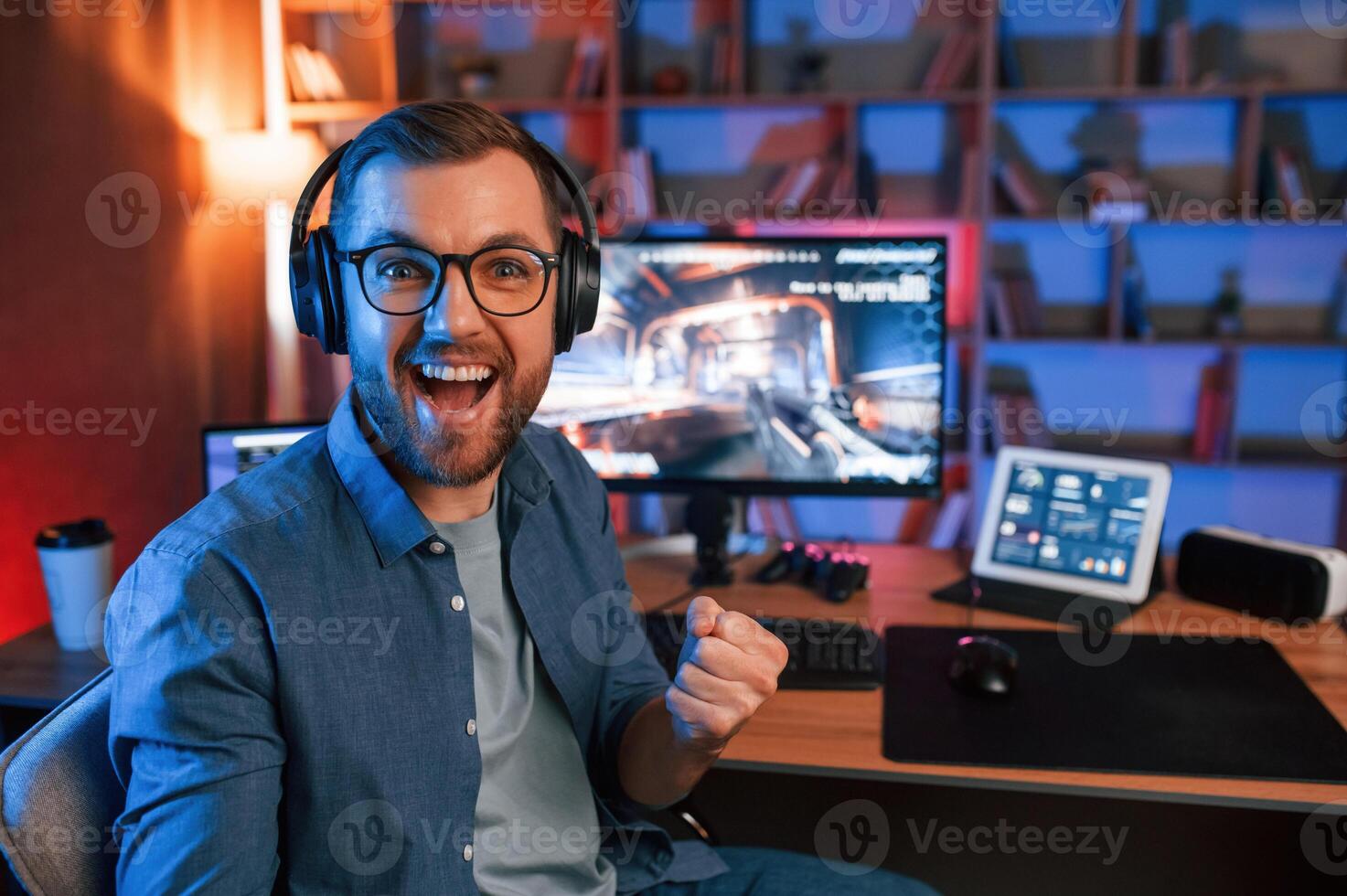 Celebrating, victory. Man is playing the shooter game on his computer. Neon lighting photo
