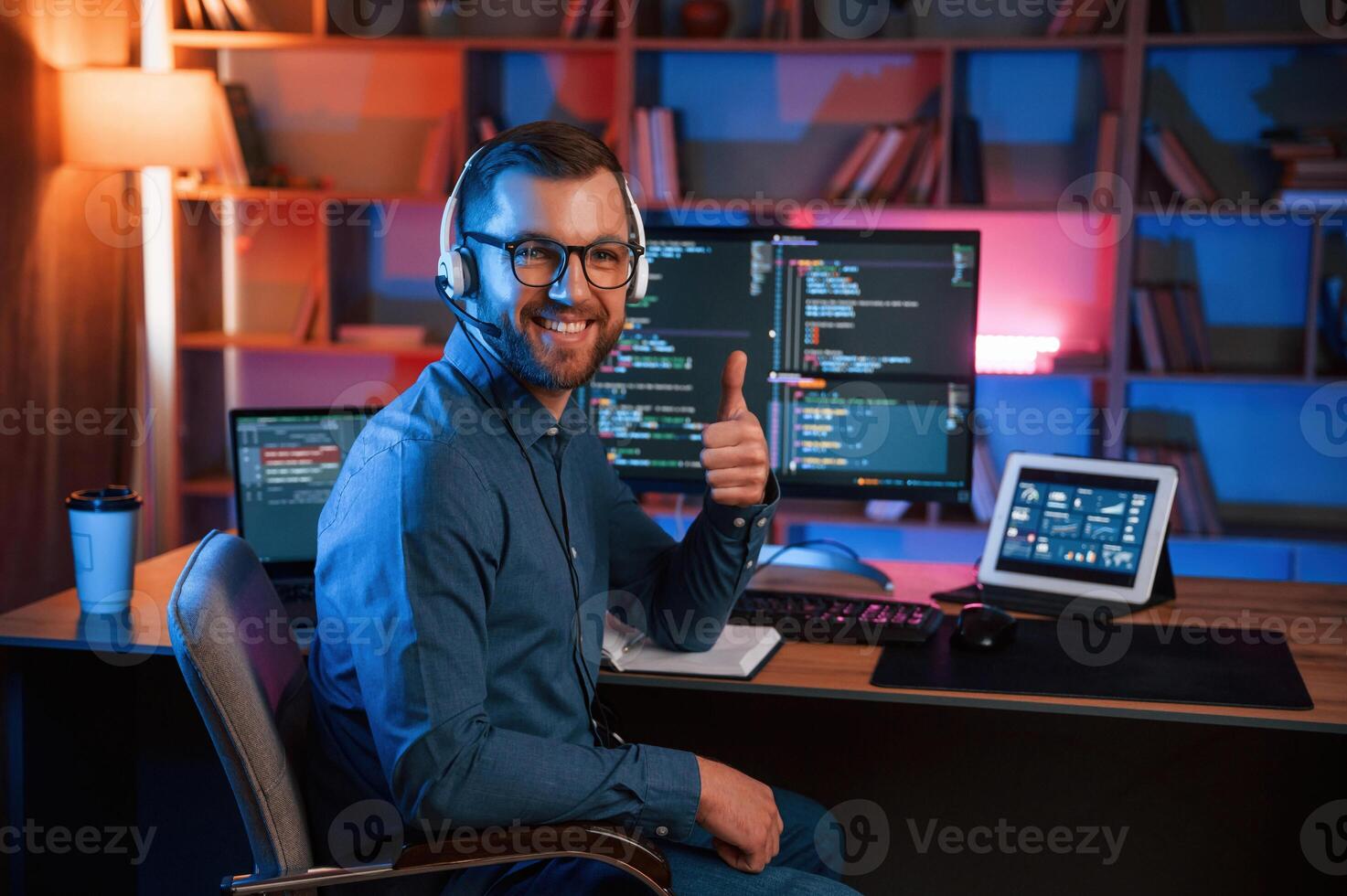Showing thumb up. Professiona,l programmer i,s working indoors. Neon lighting photo