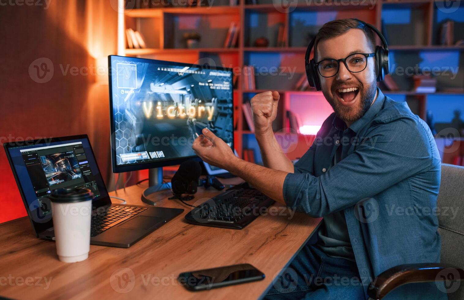 Uplifting and energized man, is playing the shooter game on his computer. Neon lighting photo