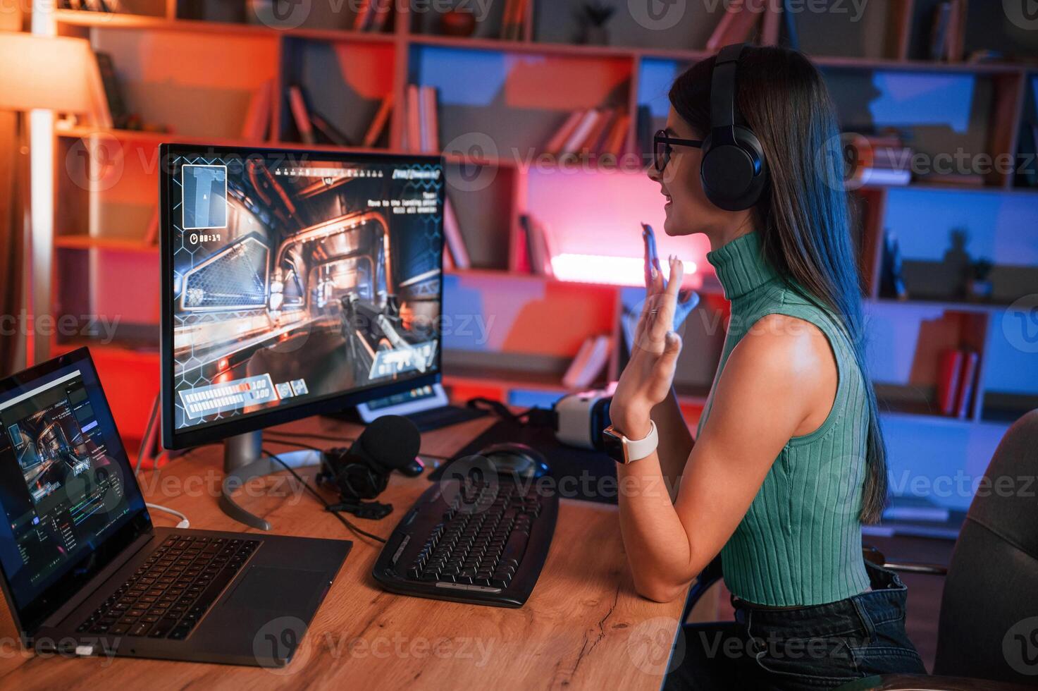 In glasses. Young pretty ,female gamer is playing shooter. Neon lighting photo