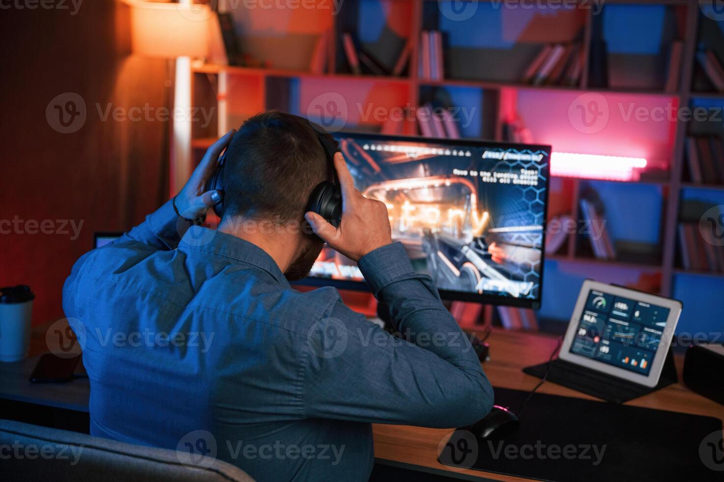 Man is playing the ,shooter game on his computer. Neon lighting photo