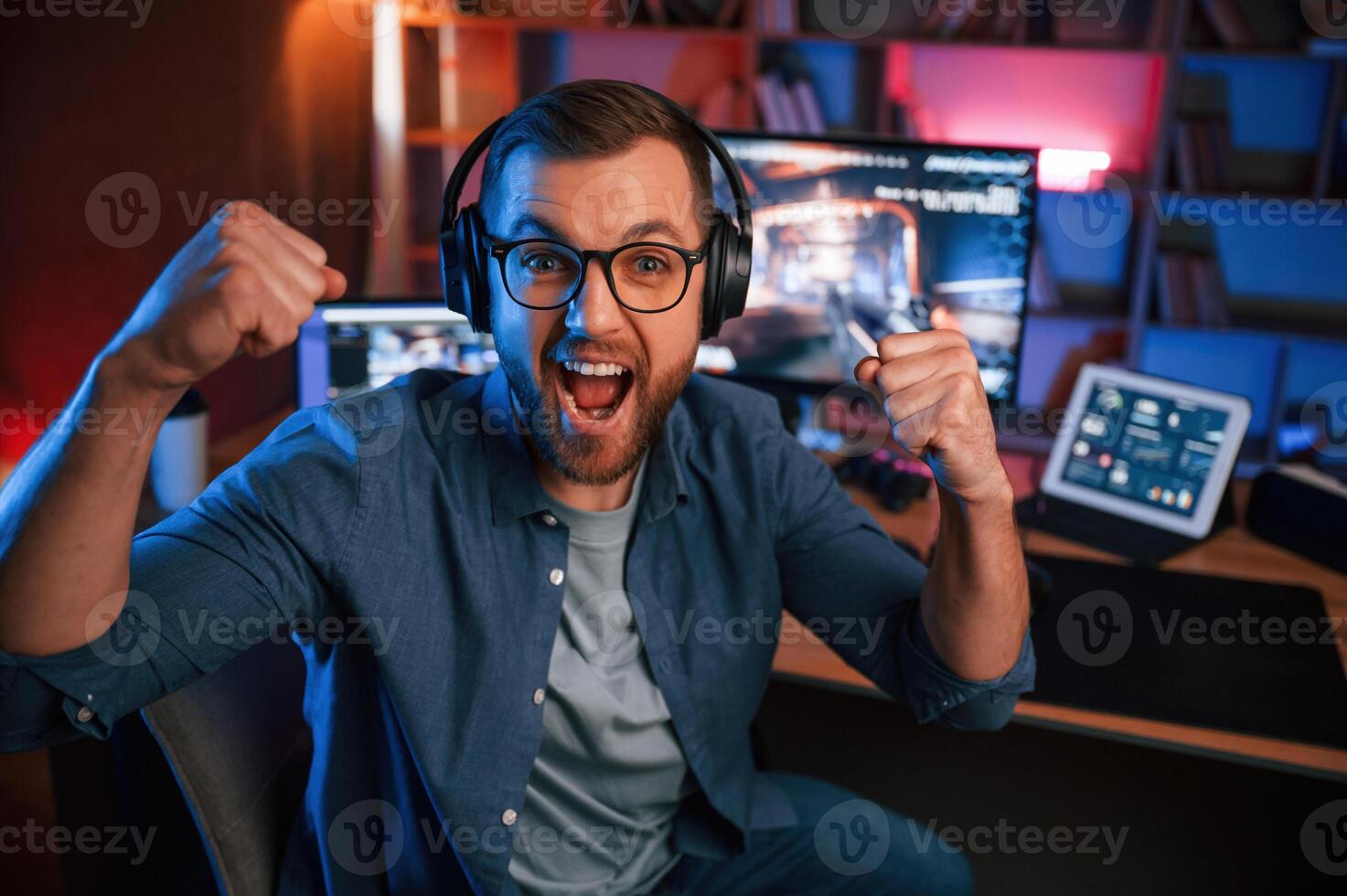 Uplifting and energized, man is playing the shooter game on his computer. Neon lighting photo