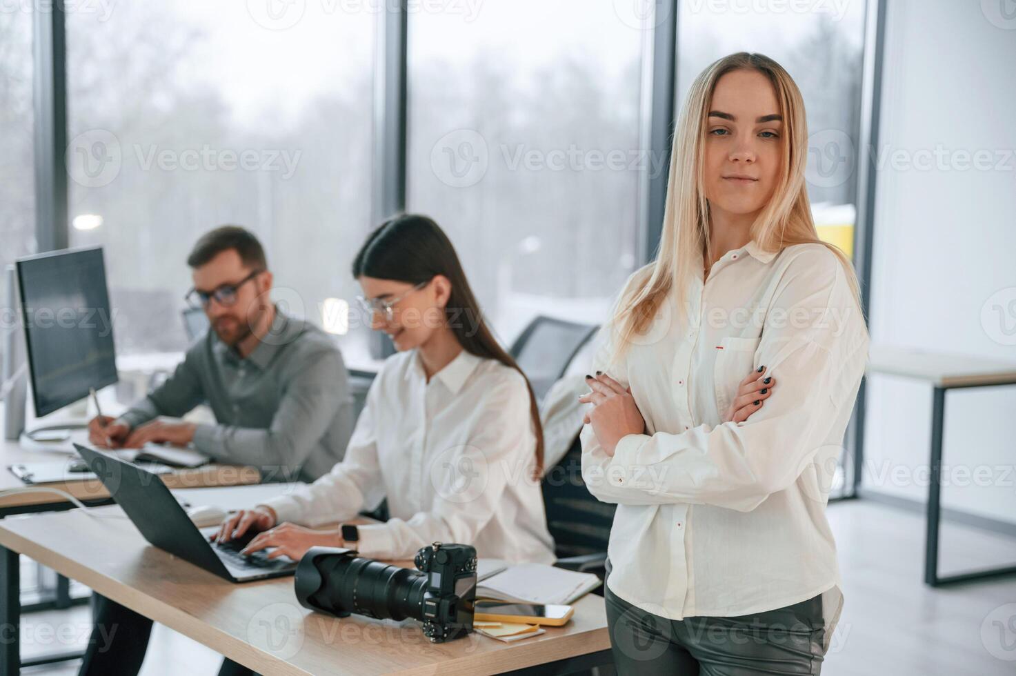 Woman is standing with arms crossed.. Successful team are working together in the office. Conception of business photo