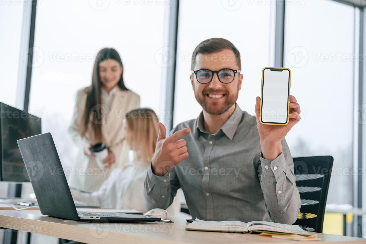 Smiling, and holding smartphone. Successful team are working together in the office. Conception of business photo