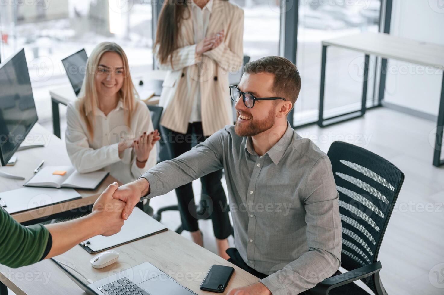 Man ,is sitting and making handshake with woman. Successful team are working together in the office photo