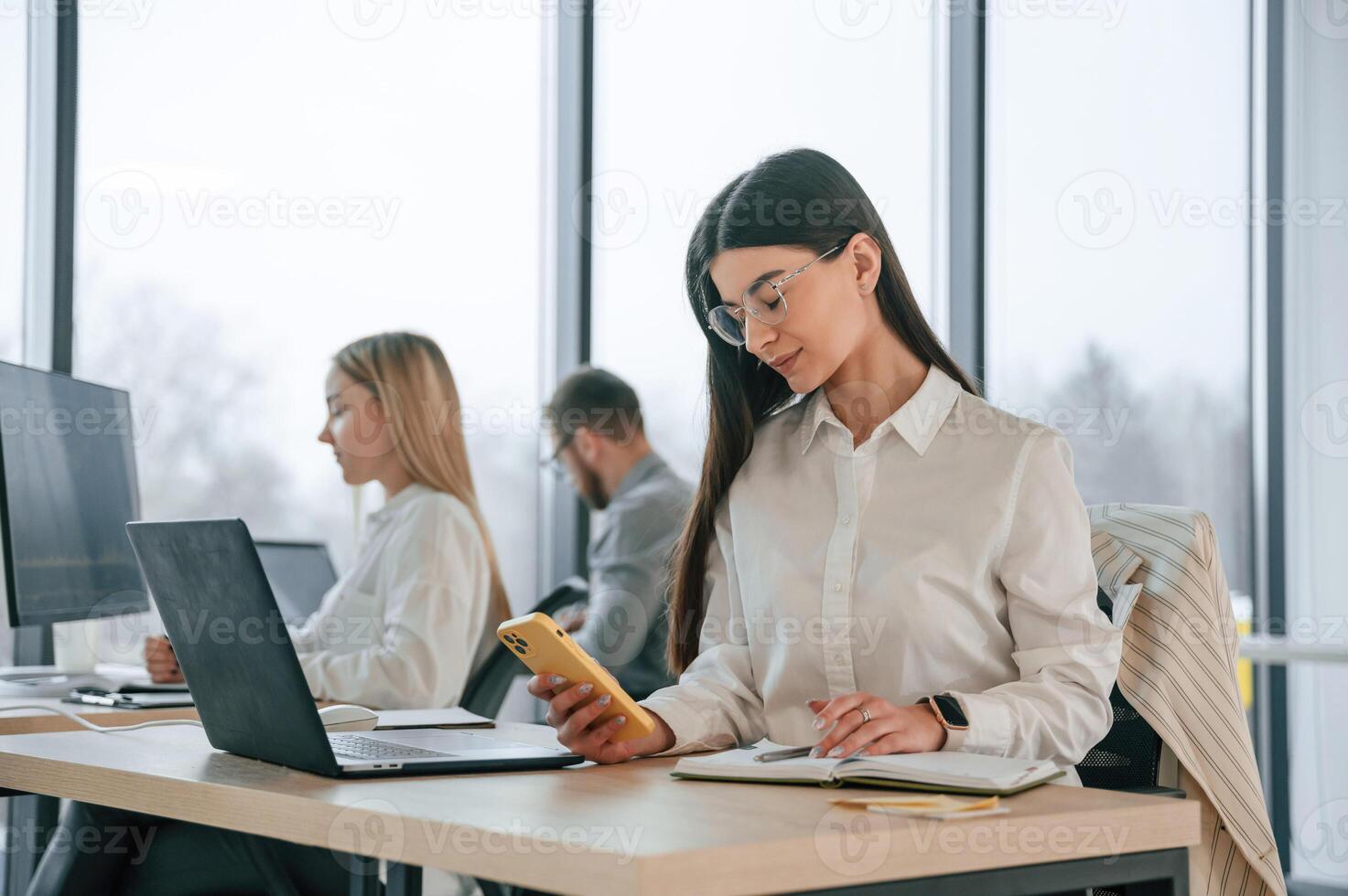 Woman is, sitting by a table with laptop. Successful team are working together in the office. Conception of business photo