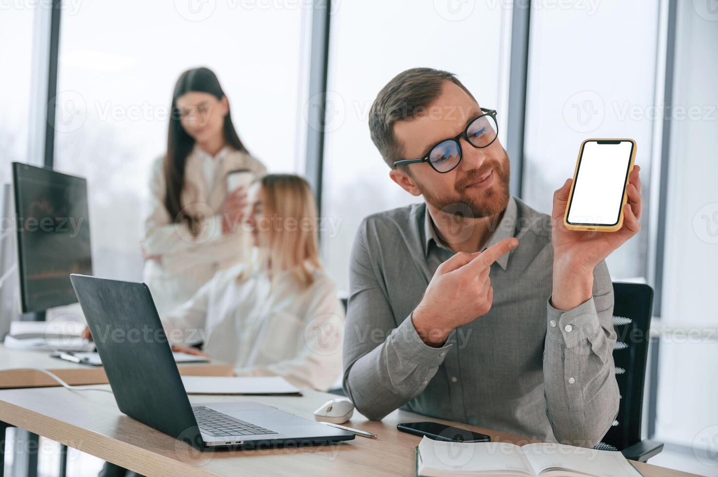 Man is ,showing information on smartphone. Successful team are working together in the office. Conception of business photo