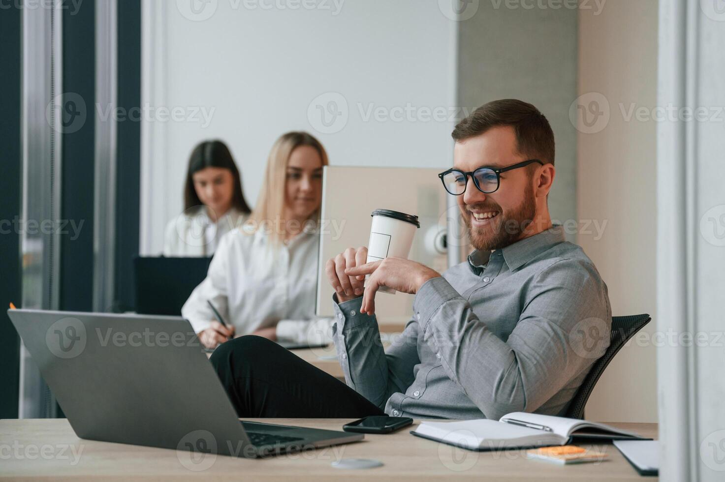 Silver colored, laptop is on the table. Successful team are working together in the office. Conception of business photo