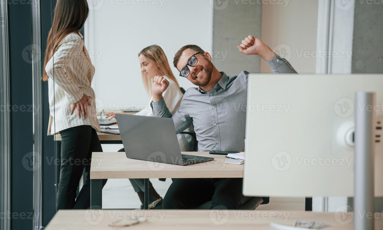 Silver colored ,laptop is on the table. Successful team are working together in the office. Conception of business photo