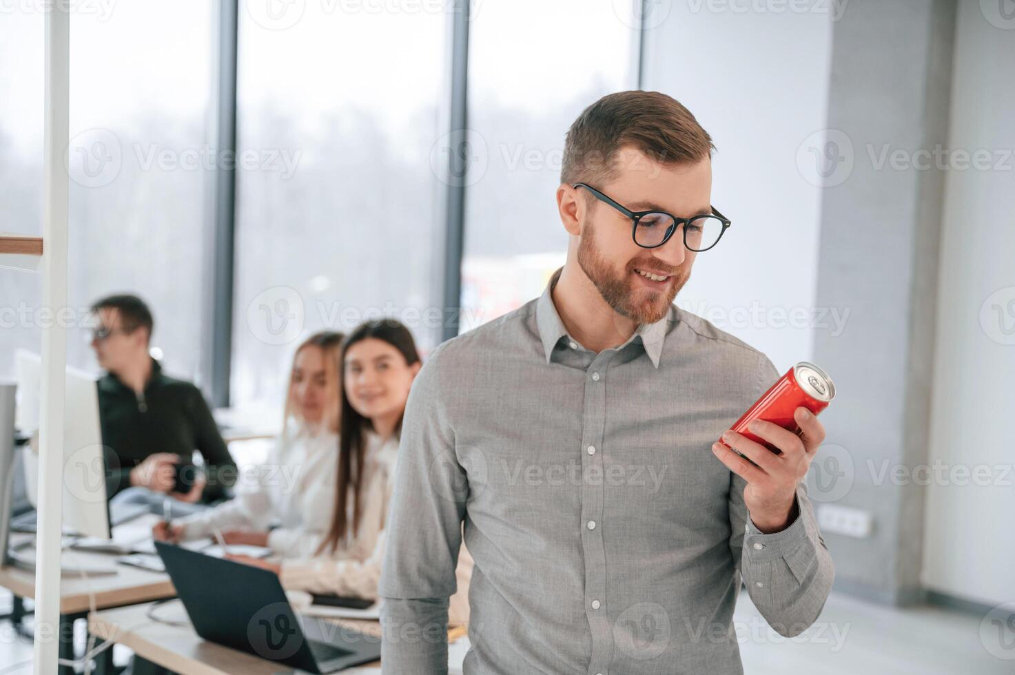 Man is holding a can with drink. Successful team are working together in the office. Conception of business photo