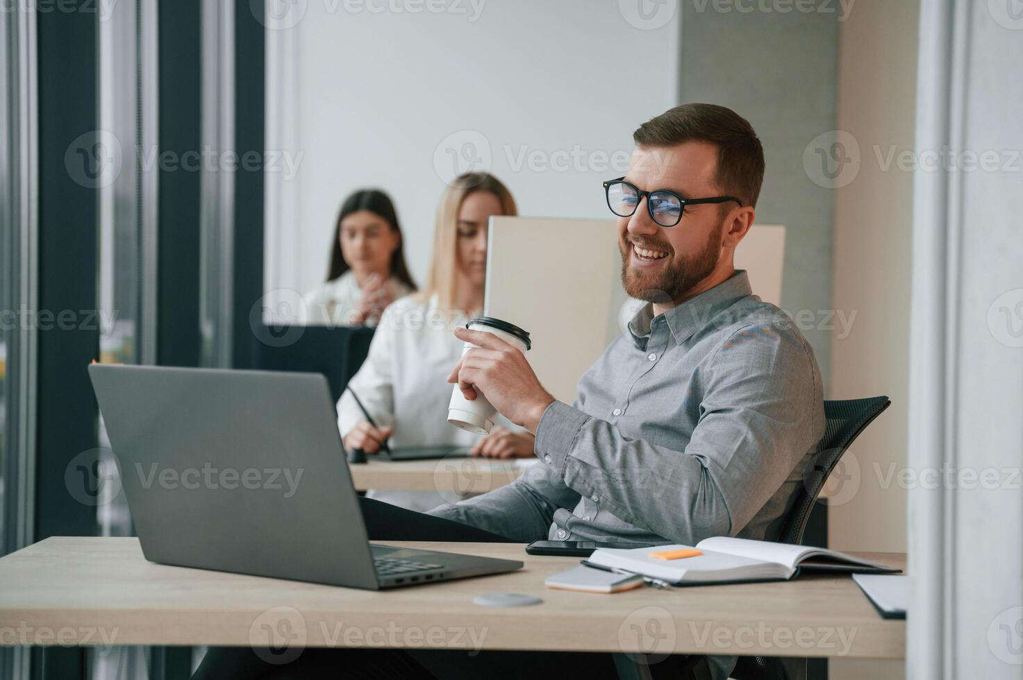 Silver colored laptop ,is on the table. Successful team are working together in the office. Conception of business photo