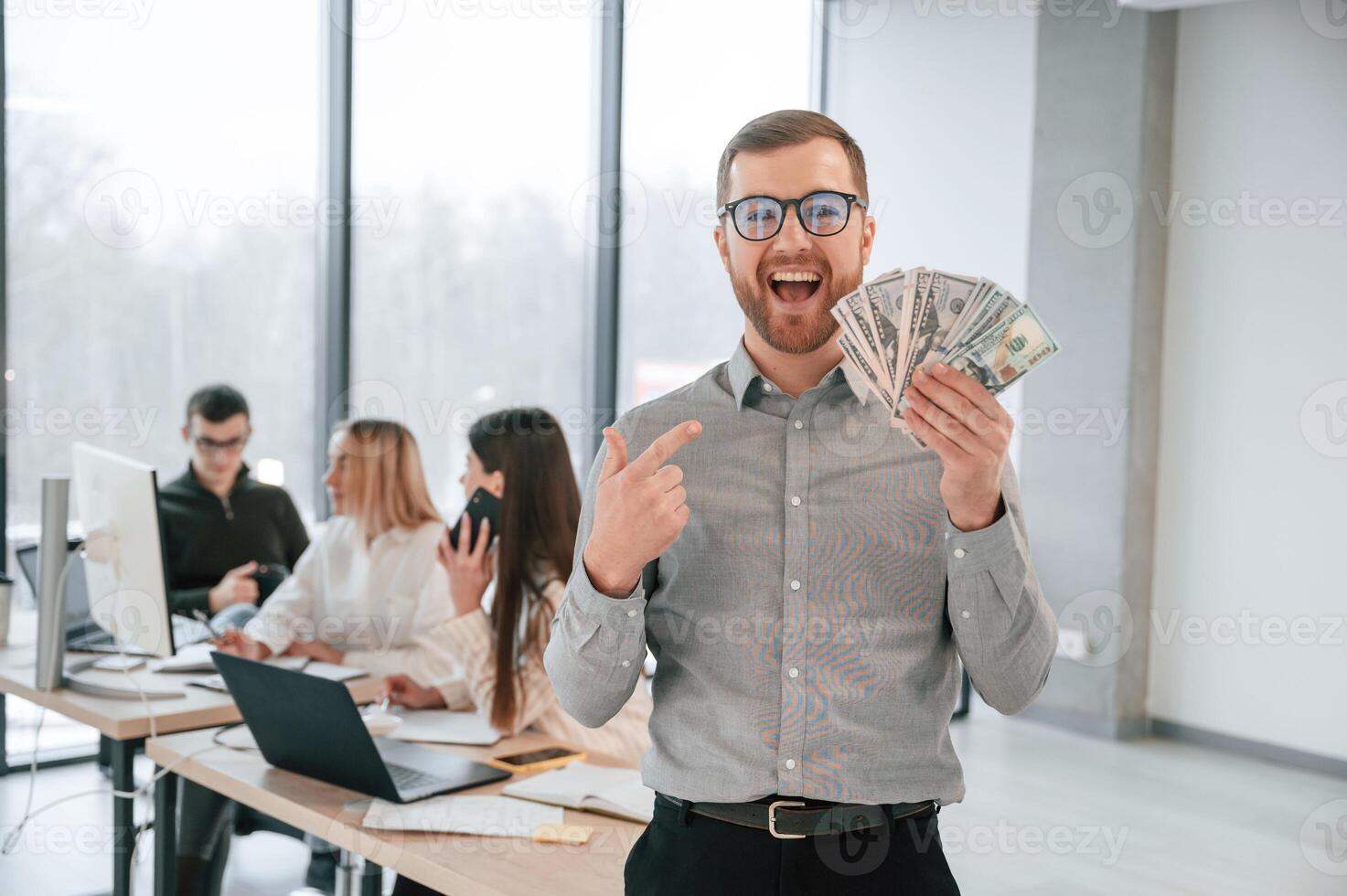 Man, ism holding money in hands. Successful team are working together in the office. Conception of business photo