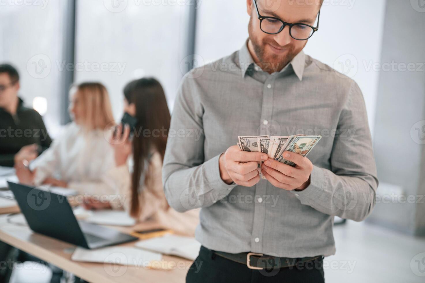 Man is holding money in, hands. Successful team are working together in the office. Conception of business photo