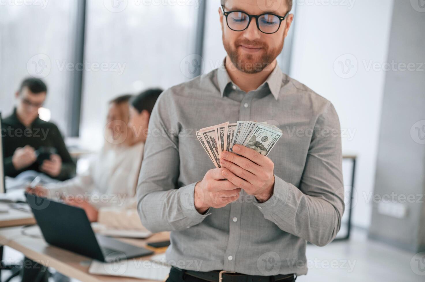 Man, is holding money in ,hands. Successful team are working together in the office. Conception of business photo