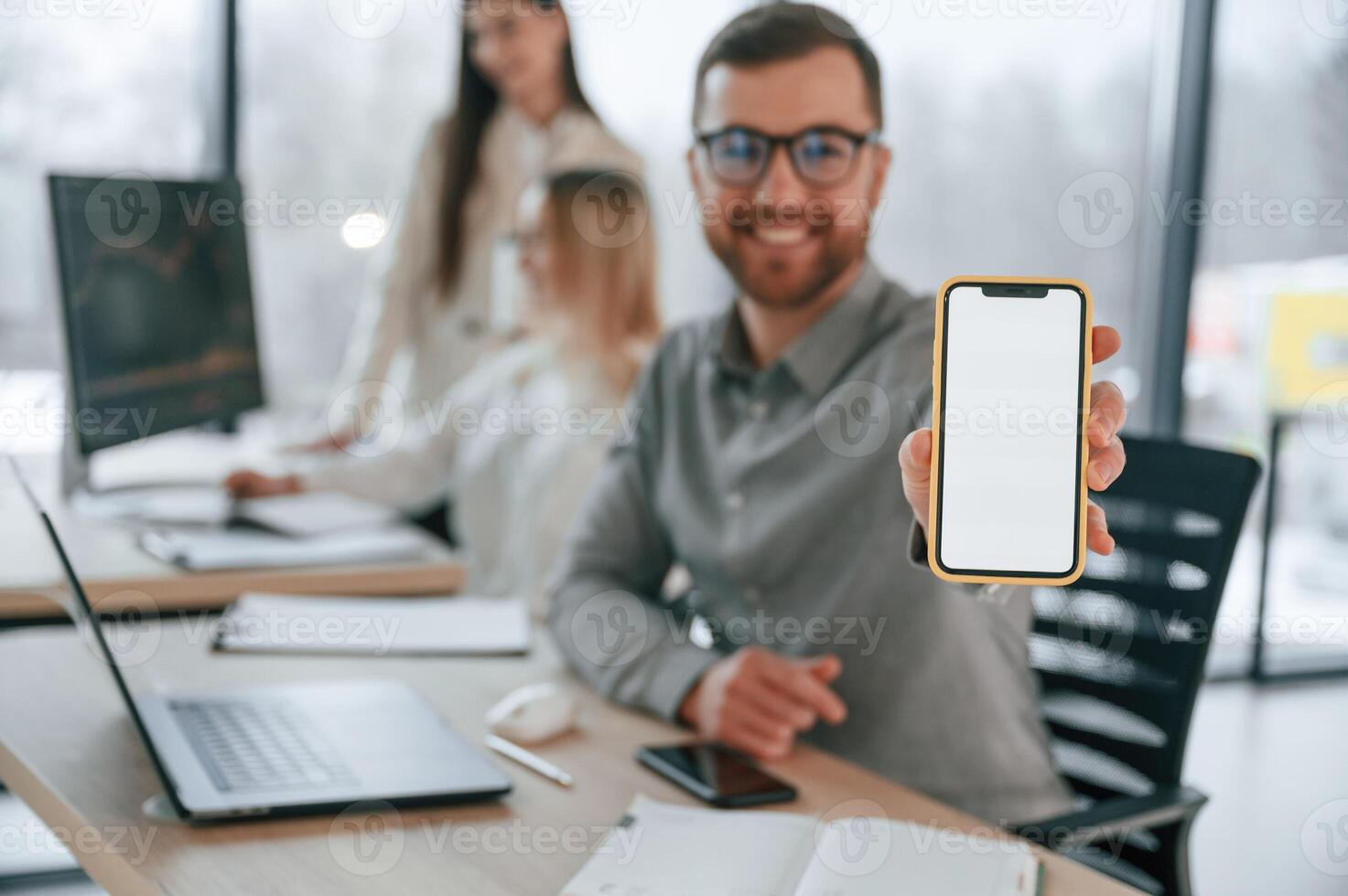 Smiling and holding smartphone. Successful team are working together in the office. Conception of business photo