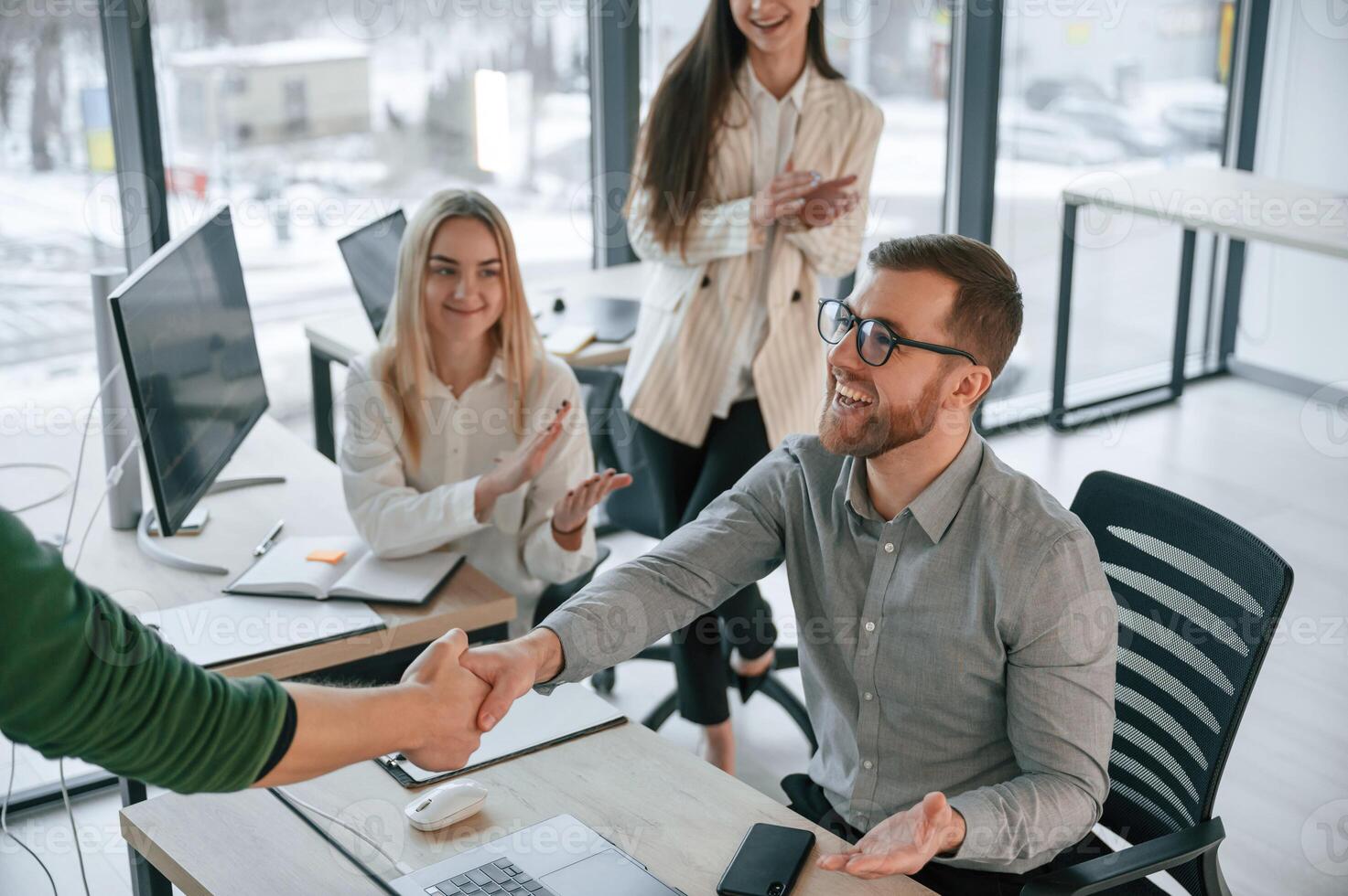 Man is sitting and making handshake ,with woman. Successful team are working together in the office photo