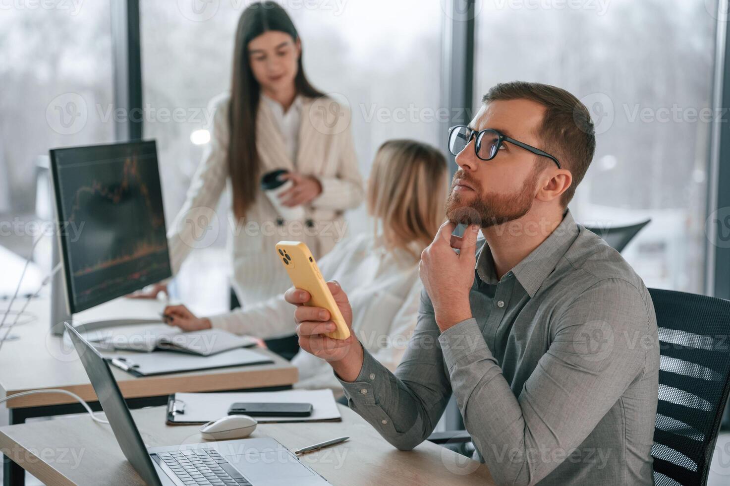 Man ,is sitting and using smartphone. Successful team are working together in the office. Conception of business photo