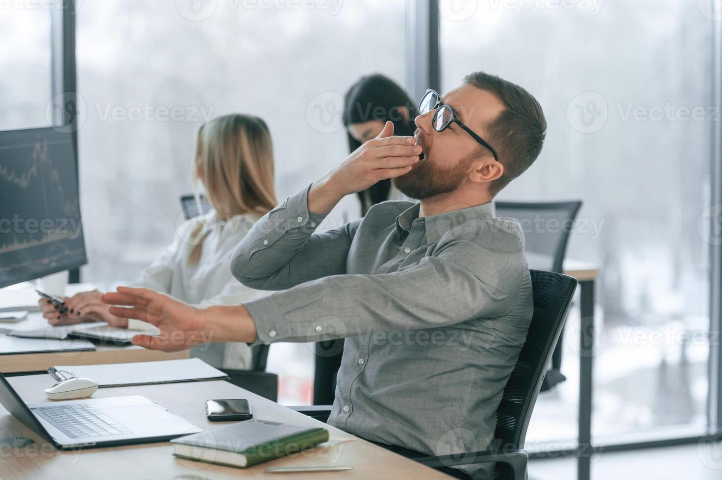 The, man yawns, wants to sleep, tired. Successful team are working together in the office. Conception of business photo