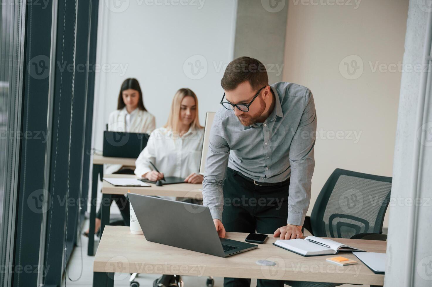 Silver colored laptop is on the table.. Successful team are working together in the office. Conception of business photo