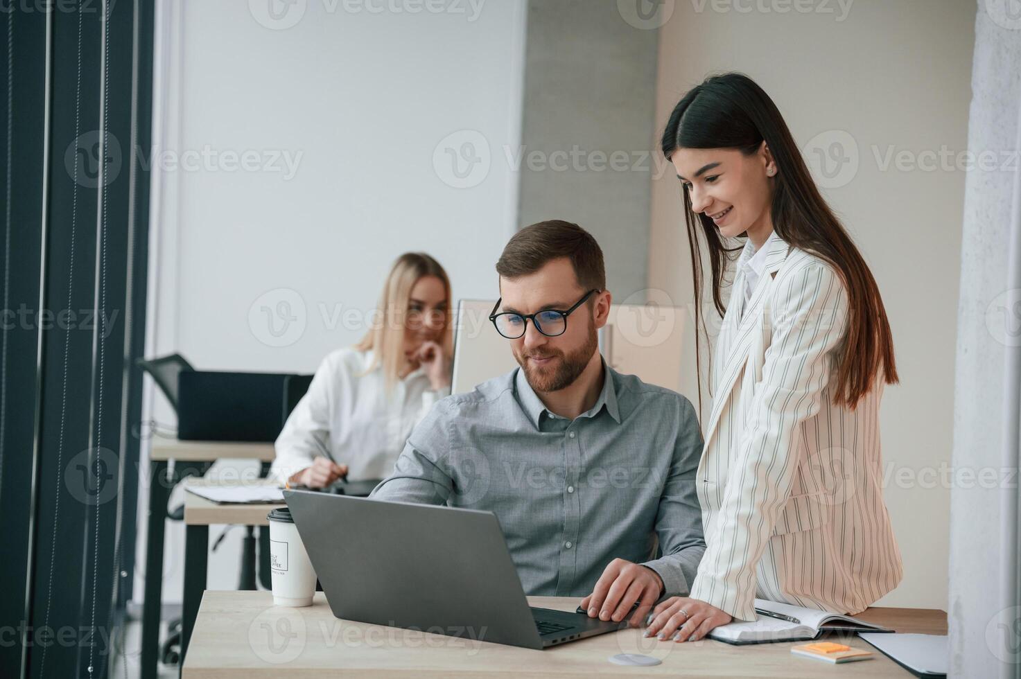 Silver colored laptop is on the table. Successful, team are working together in the office. Conception of business photo