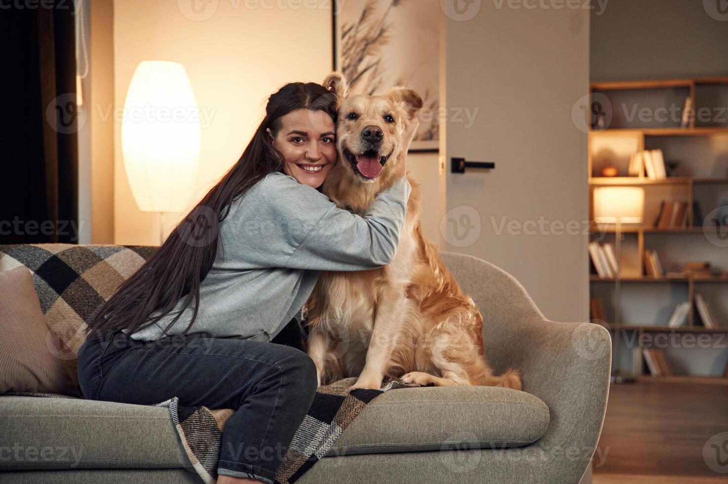 Playing, and sitting on the sofa. Woman is with golden retriever dog at home photo