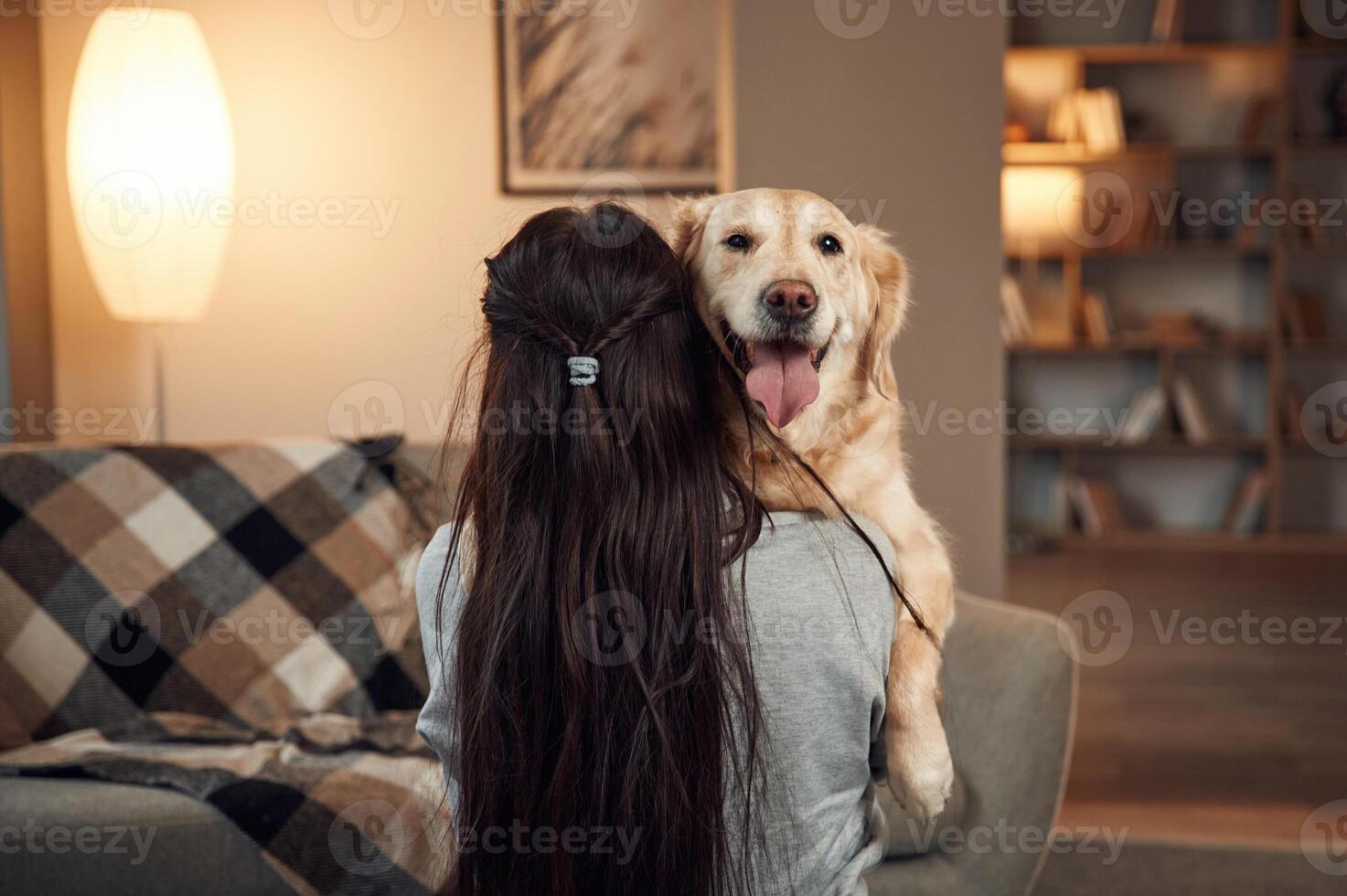 Holding dog in the hand.s. Woman is with golden retriever at home photo