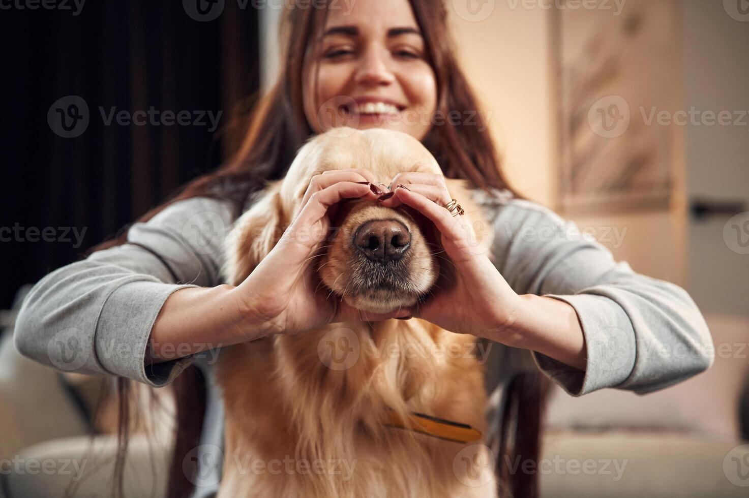 Covering face with hands. Love gesture. Woman is with golden retriever dog at home photo