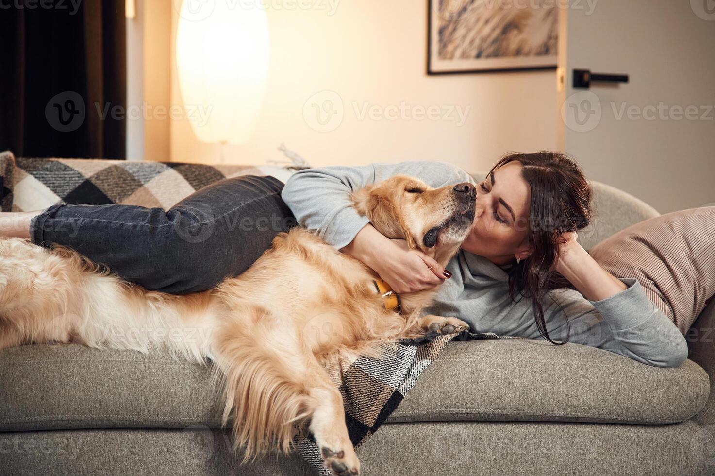Lying,, down on the sofa together. Woman is with golden retriever dog at home photo