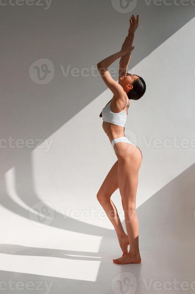 View, from the ,side. Young caucasian woman with slim body shape is indoors in the studio photo