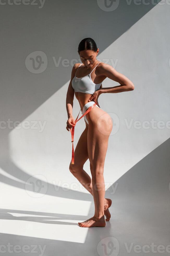 Beautifu,l shadows from sunlight. Young caucasian woman with slim body shape is indoors in the studio photo