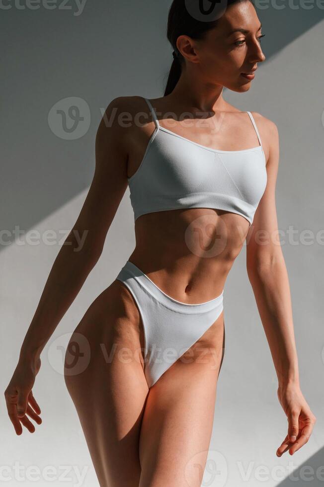 Showing, new collection of underwear. Young caucasian woman with slim body shape is indoors in the studio photo