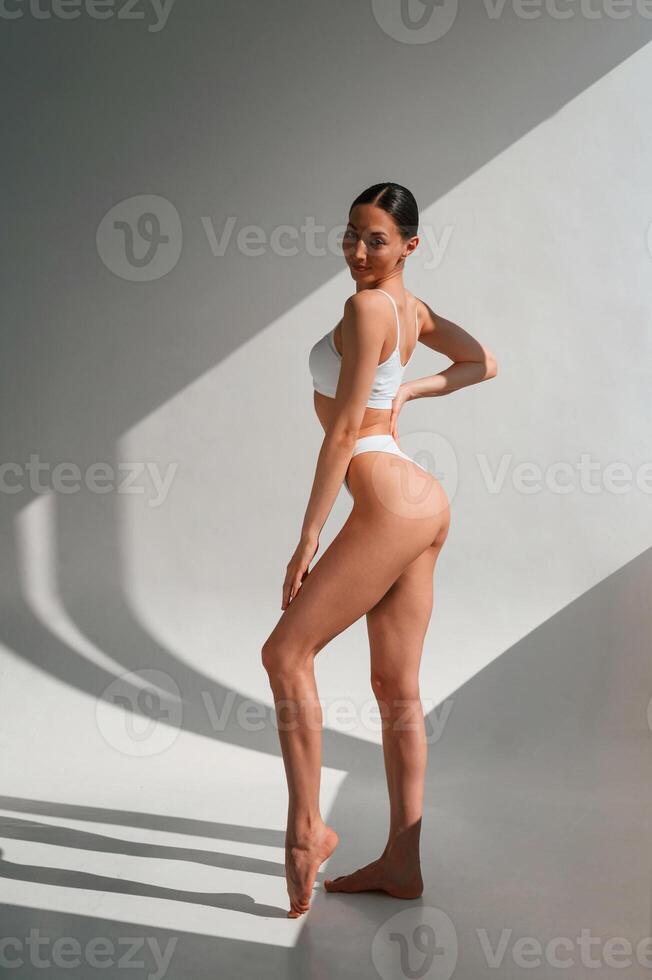 View ,from the side. Young caucasian woman with slim body shape is indoors in the studio photo