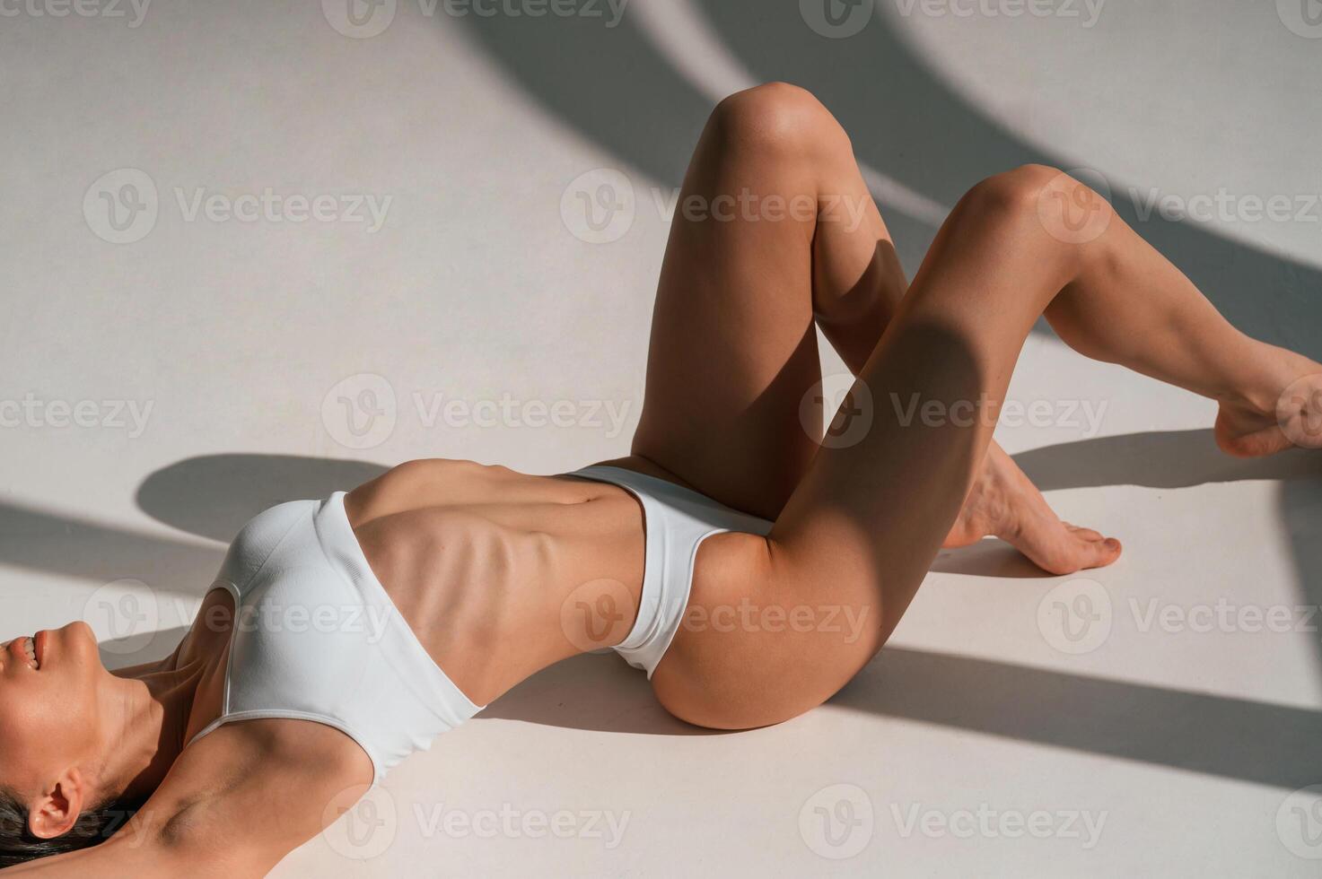 Lying down ,on the ground. Close up view. Young caucasian woman with slim body shape is indoors in the studio photo