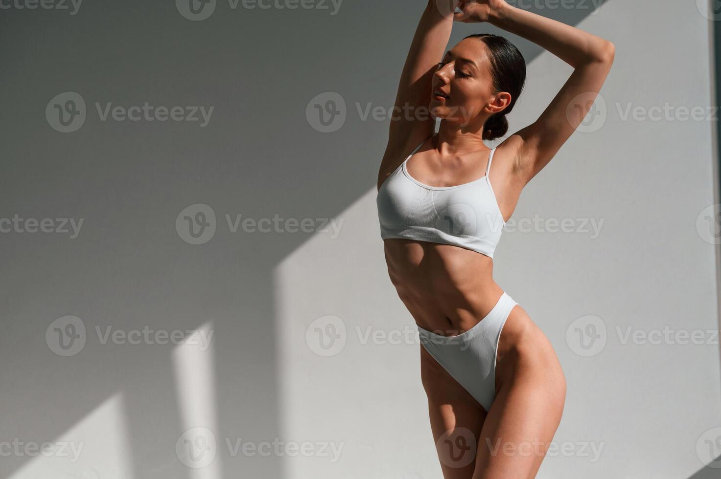 Woman, with slim body shape is indoors in the studio. Model is posing photo
