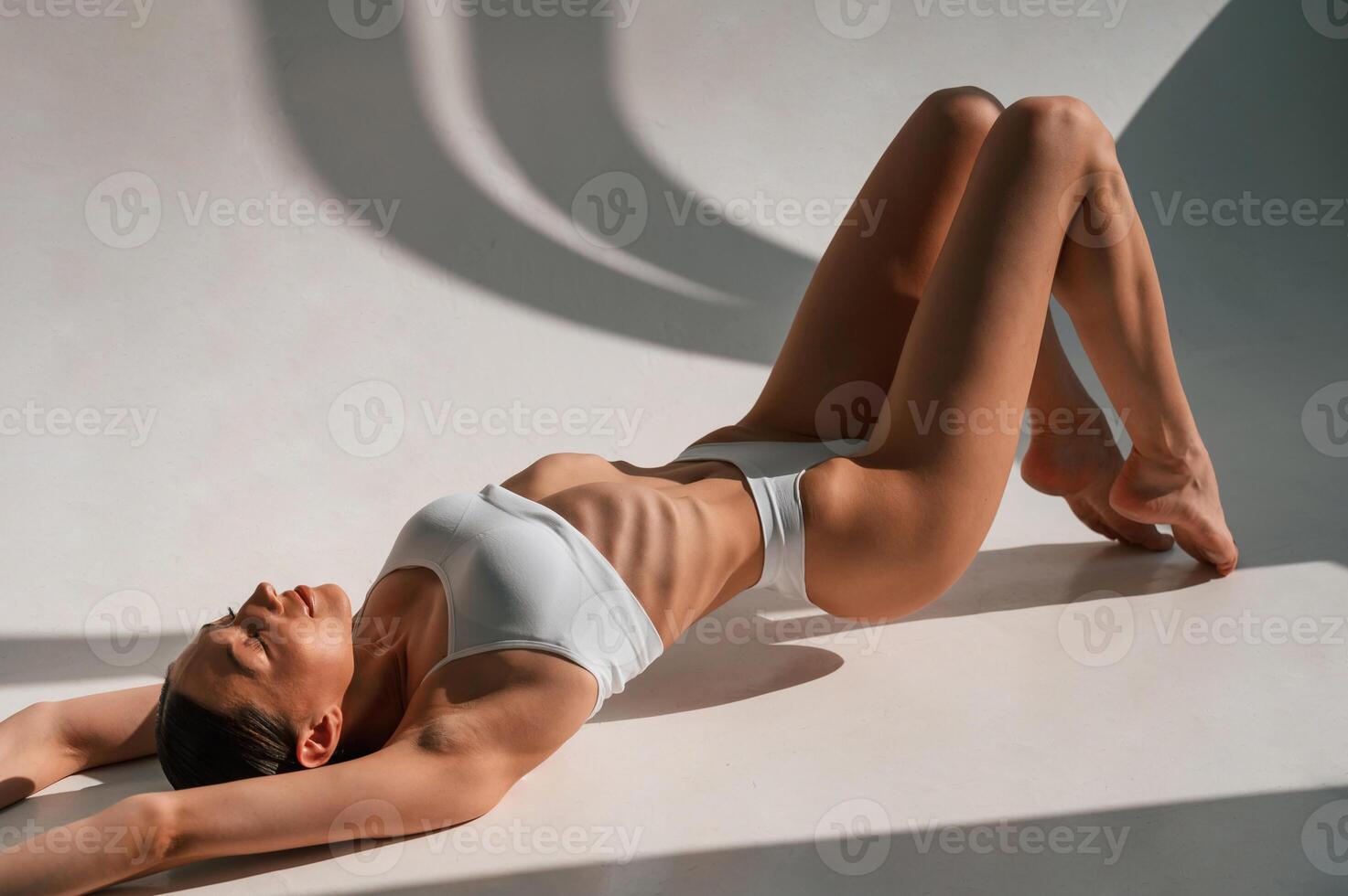 Peaceful, mood. Lying down on the floor. Young caucasian woman with slim body shape is indoors in the studio photo