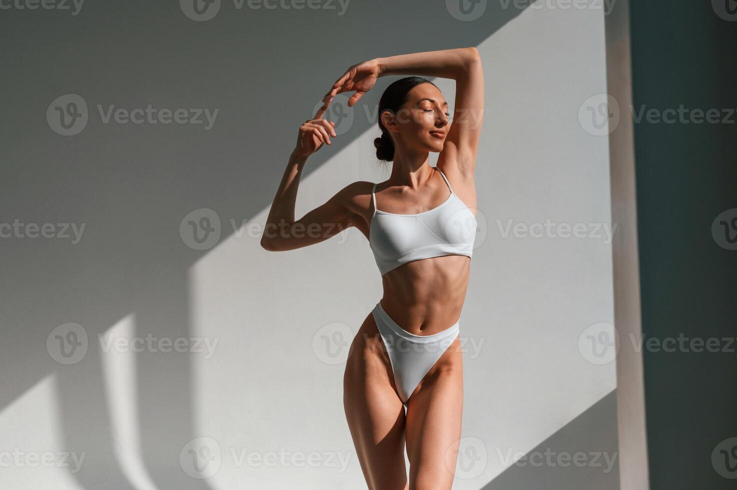 Feeling good, enjoying ,warmth of the sunlight. Young caucasian woman with slim body shape is indoors in the studio photo