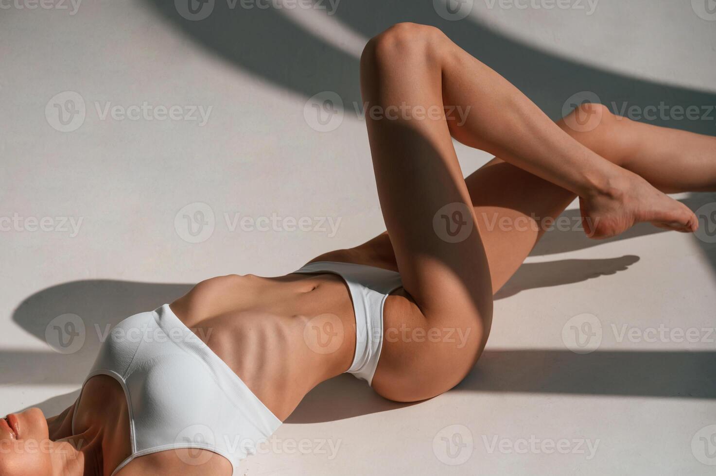Resting on the floor.. Young caucasian woman with slim body shape is indoors in the studio photo